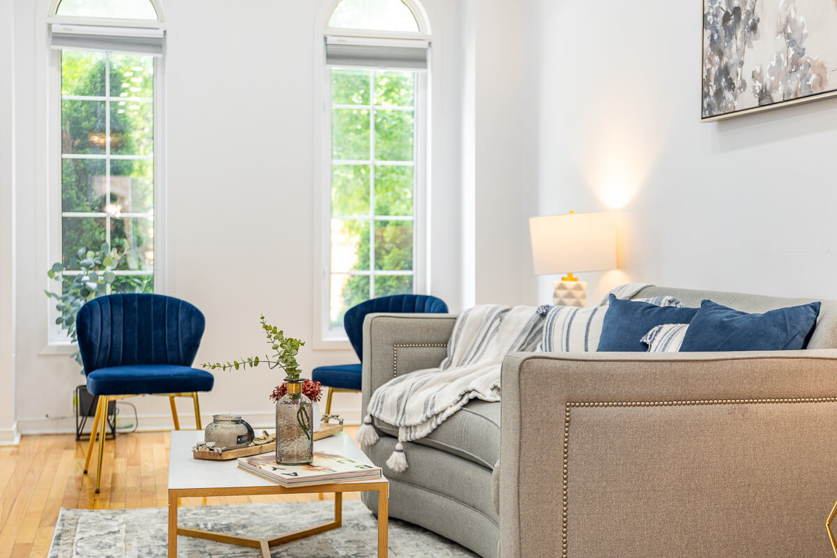 Bright living room with large windows, blue accent chairs and modern decor, real estate photography Toronto