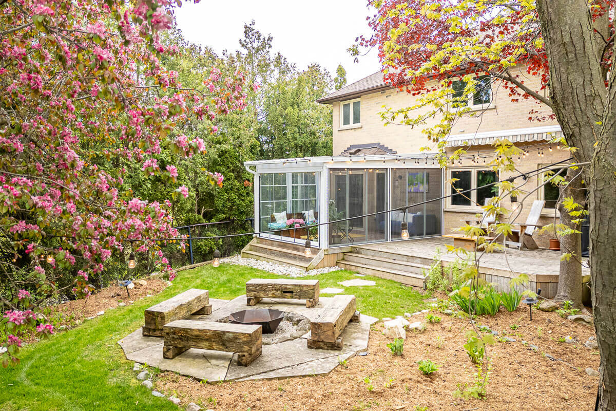 Backyard with fire pit and deck surrounded by trees, aerial real estate photography Toronto