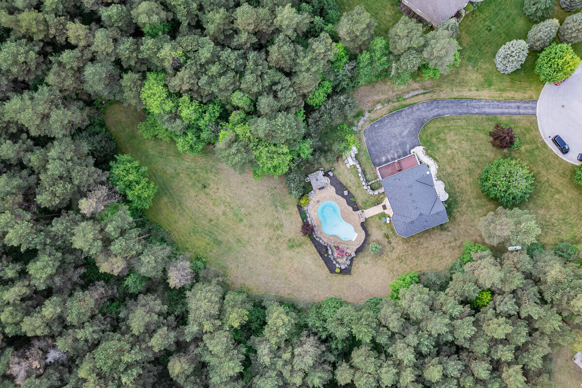 Aerial view of house surrounded by forest and large lot, drone real estate photography Ontario