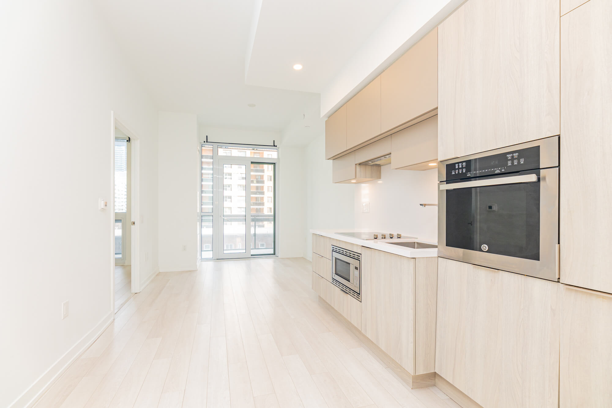 Empty living room before virtual staging in Toronto condo with modern kitchen and large windows